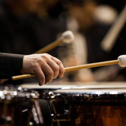 Hands musician playing the timpani in the orchestra closeup in dark colors